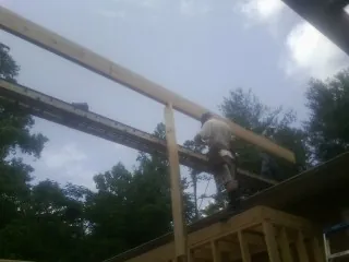 Carpenter setting a ridge beam over a new addition frame — Ice Dam Removal by Roofing Brothers in Hobart