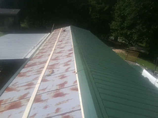 Old rusted panels beside newly installed green metal roofing — Wind Damage Roof Repair by Roofing Brothers in Hobart