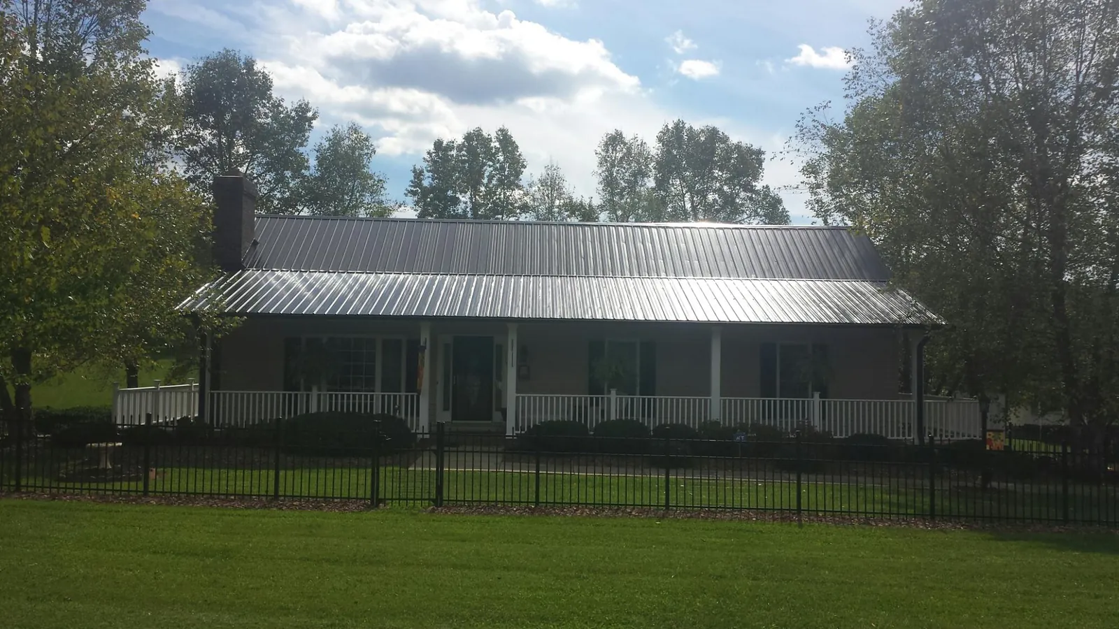 Gray metal roof on a brick ranch with a full width front porch — Gutter Guard Installation work by our crew in Hobart