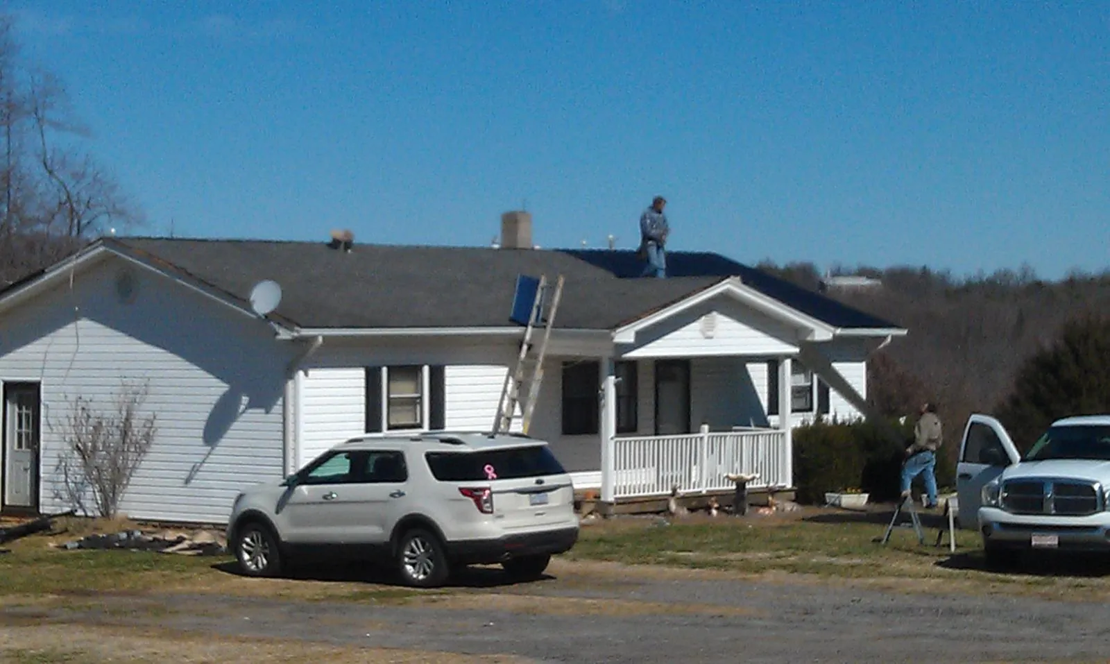 Roofers stripping shingles from a white ranch house roof in Hobart