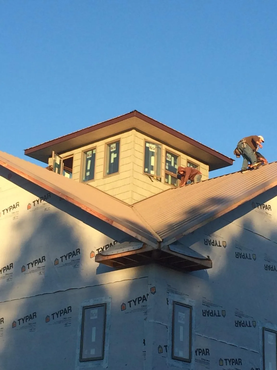 Roofers working around a rooftop cupola on a new metal roof at sunset — Roof Waterproofing in Hobart by Roofing Brothers